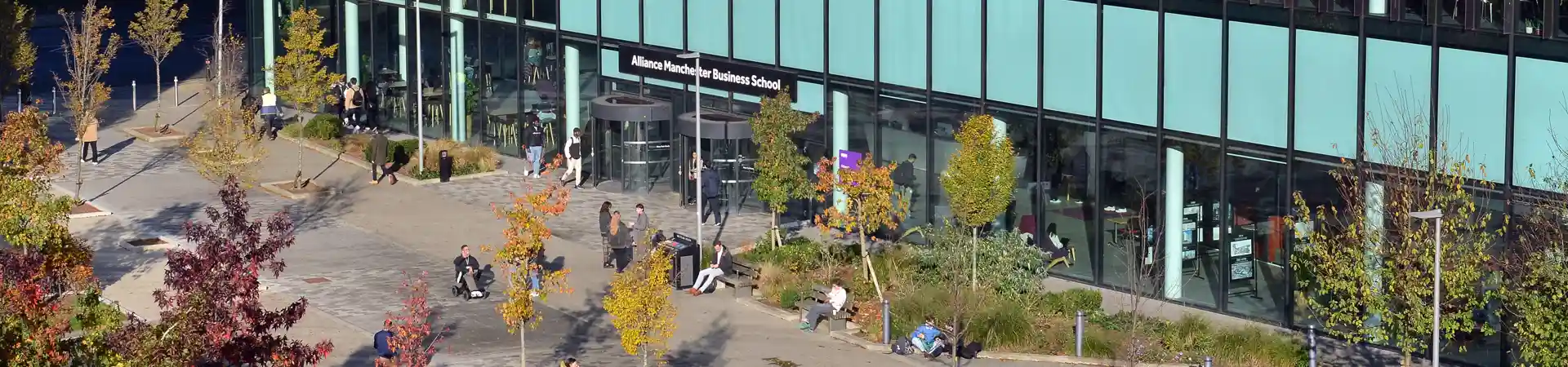 An aerial view of the AMBS building entrance with students and staff members