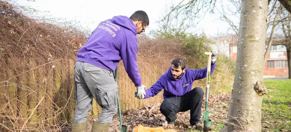 Two Manchester students working together to clean a street