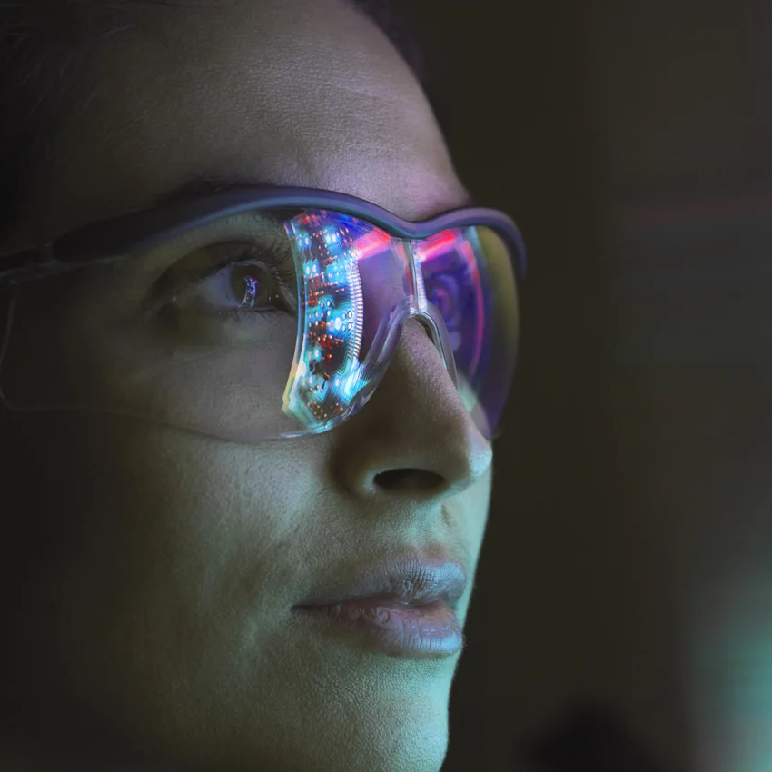 A person looking at a screen with glasses on. We can see the reflection of the screen in the glasses.