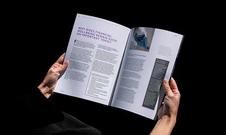 Hands holding the Alliance MBS magazine open at a finance article