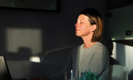 Woman closing her eyes as the last sun rays of the day come into her house