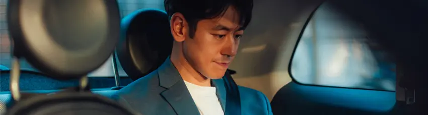 Asian male entrepreneur working on digital tablet while traveling by a car.
