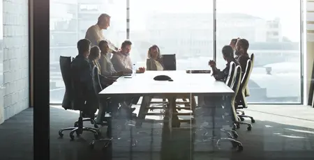 CEO giving peptalk to businesspeople at meeting in big conference room.