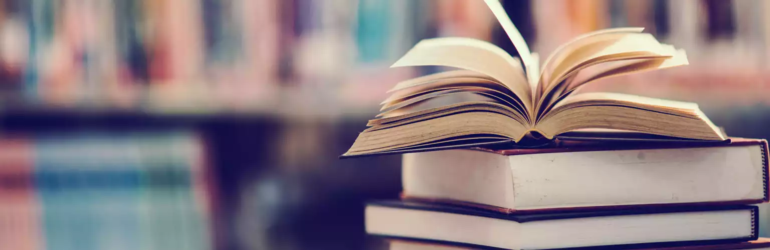 Books on a table leaning against a shelf