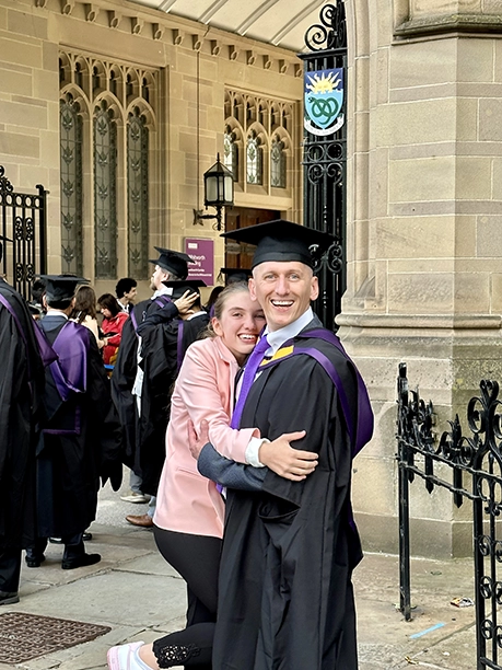 student with daughter in graduation gown