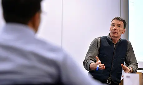 An academic professor teaching at the front of a classroom