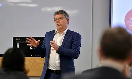An academic professor teaching at the front of a classroom