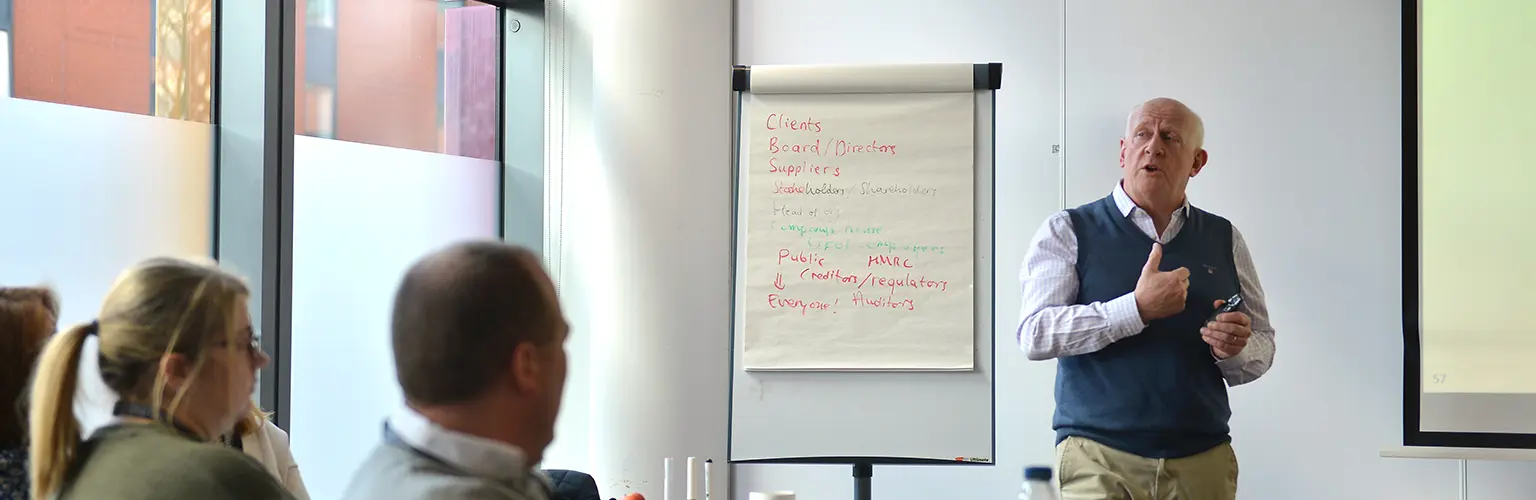 An academic professor teaching at the front of a classroom