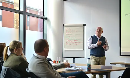 An academic professor teaching at the front of a classroom